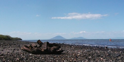 Baignade sur la plage de Potosí. On voit à l'arrière-plan plusieurs volcans du Honduras